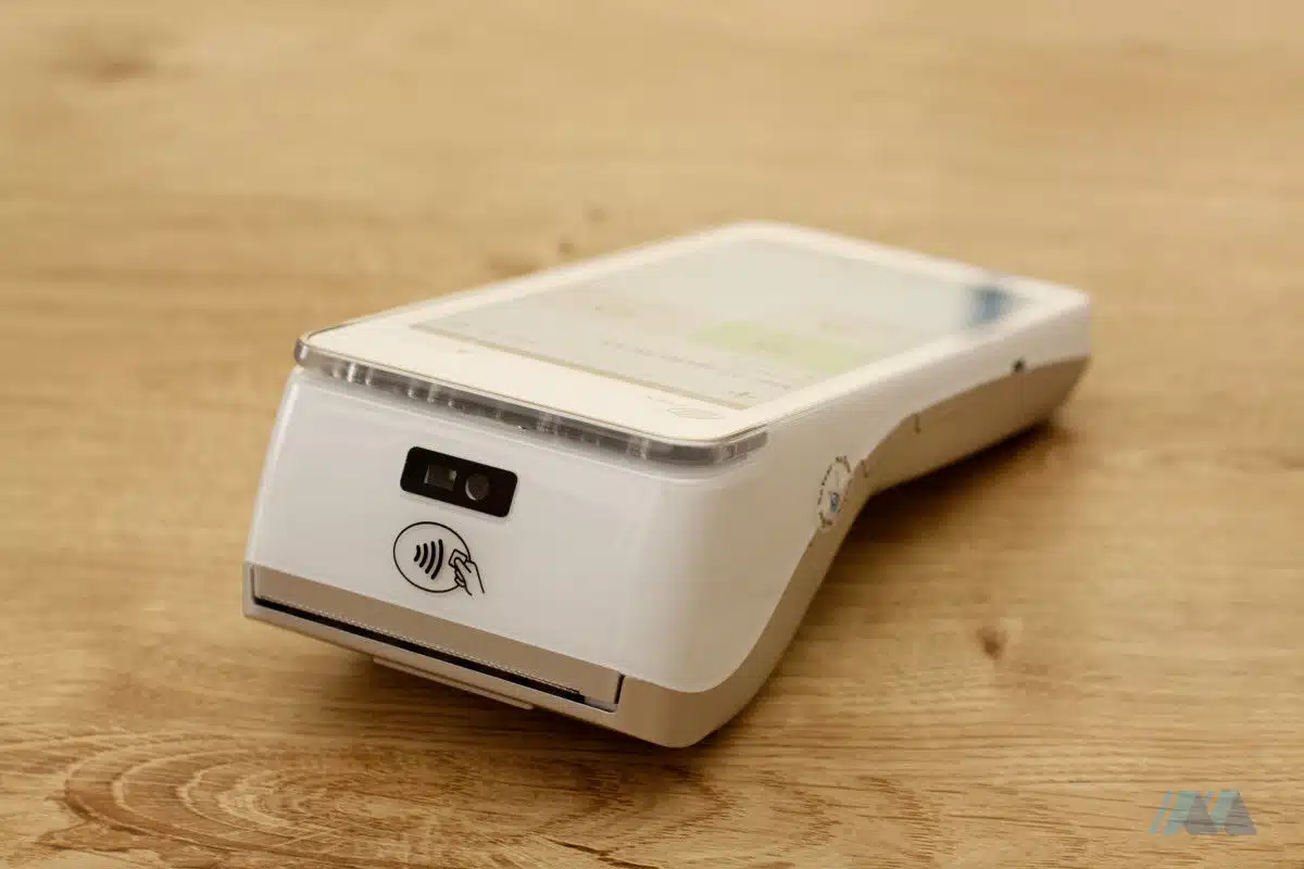 Vista del lato posteriore del dispositivo POS Flatpay, che mostra lo scanner di codici a barre, la zona NFC e la fessura di uscita dello scontrino di pagamento