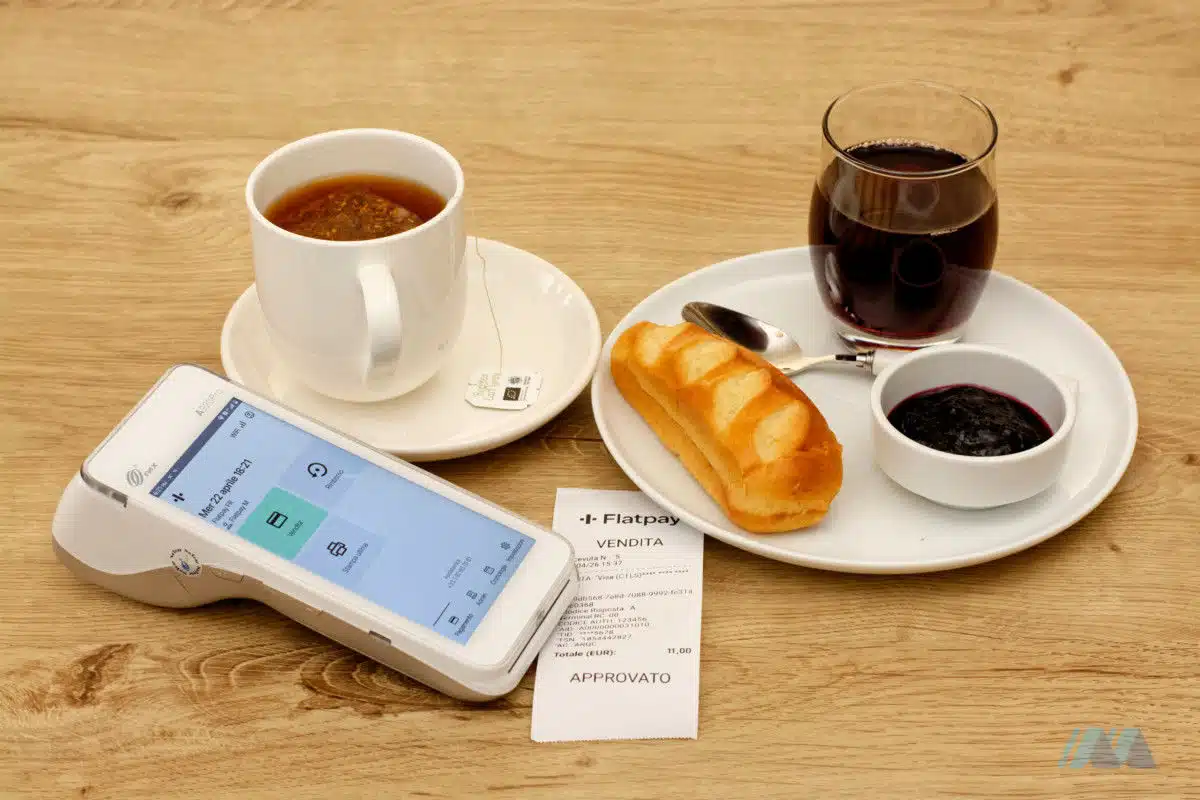 Terminale POS Flatpay su un tavolo accanto a una colazione servita in un barar
